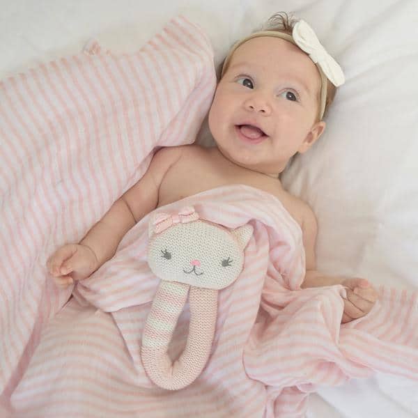 Baby-girl-smiling-cat-rattle-adn-blush-stripe-muslin-swaddle-web-grande